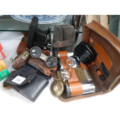 556 - A mixed lot of leather cased shaving sets, binoculars, camera etc.,