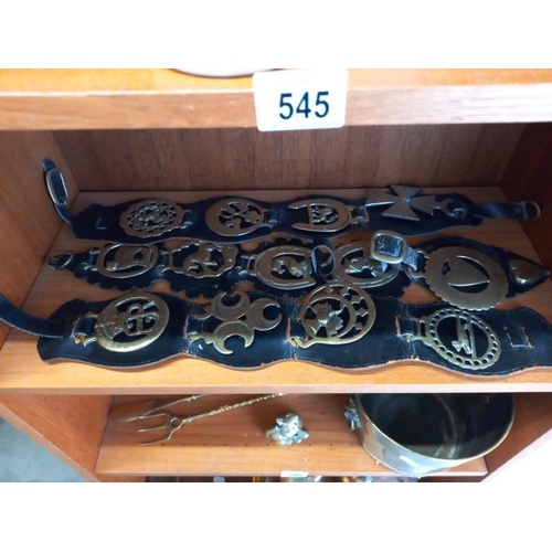 546 - Brassware including toasting forks, shells case, horse brasses etc, 3 shelves.