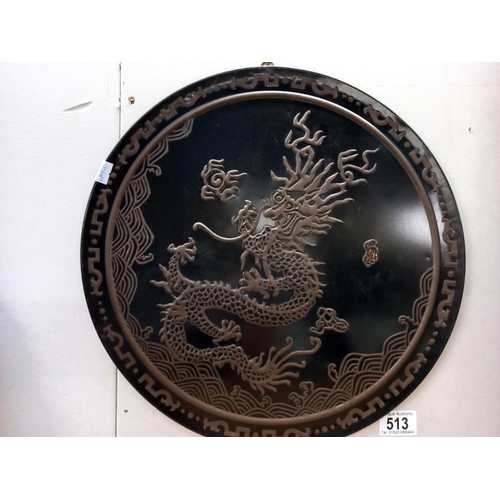 513 - An embossed oriental tin wall plaque of a dragon. Diameter 39cm.