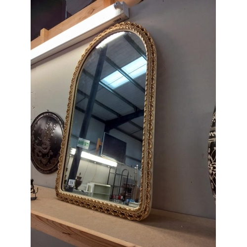 514 - An ornate gilt framed arched mirror. 52cm x 83cm.