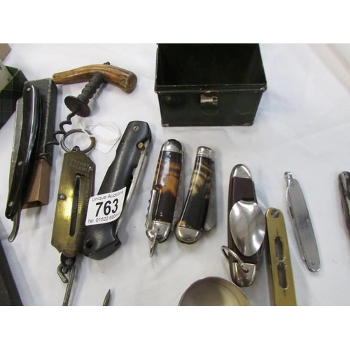 763 - A tray of vintage pocket knives, cork screws, small brass spirit level etc.,