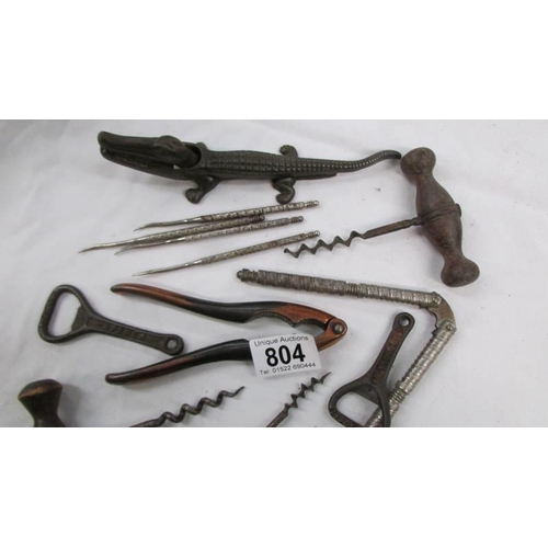 804 - A vintage cast iron crocodile nut cracker, cork screws and bottle openers.