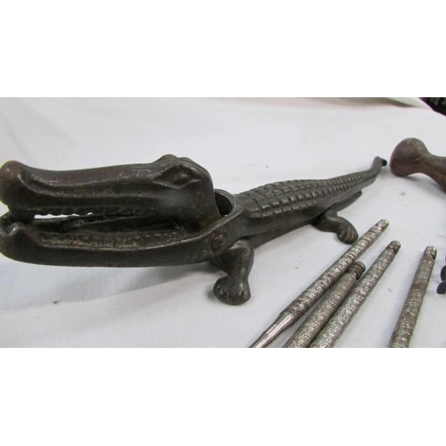 804 - A vintage cast iron crocodile nut cracker, cork screws and bottle openers.