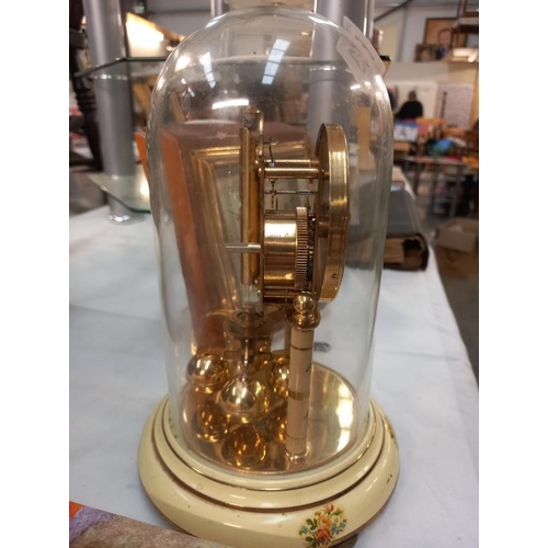 663 - A Bentima floral pattern anniversary clock under glass dome and a vintage barometer.