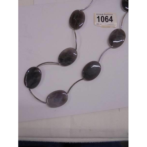 1064 - A long silver stone set necklace.