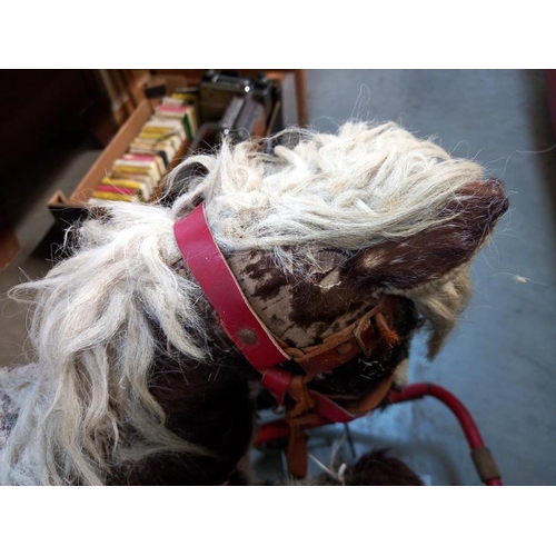 741 - A vintage straw filled rocking horse on folding wheels