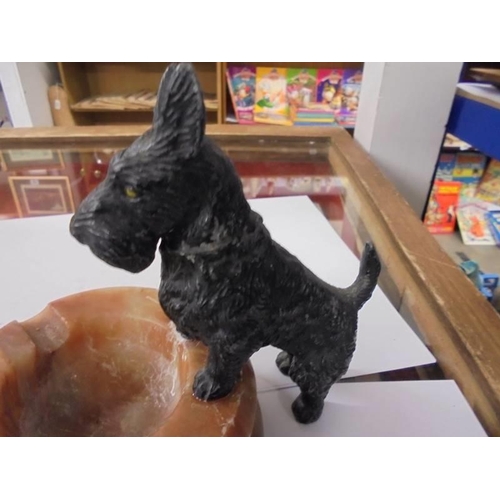 681 - An art deco spelter scottie dog standing on an onyx ashtray.