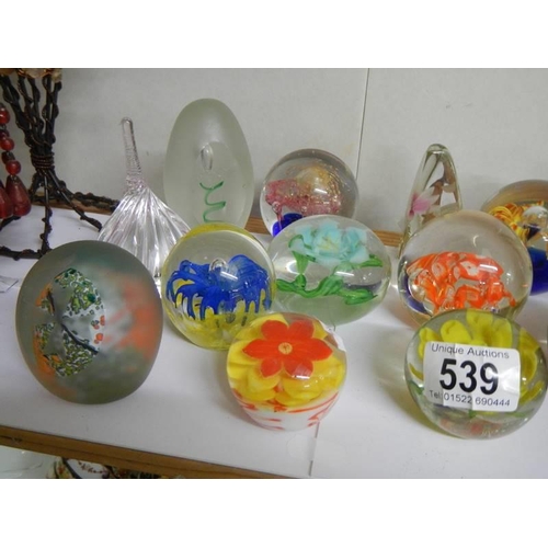 539 - A shelf of assorted paperweights.