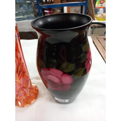 654 - A glass vase in black and decorated with roses together with a pale orange pressed glass vase.