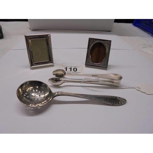 110 - An EPNS sugar sifter spoon, sugar tongs and two miniature photo frames.