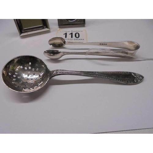 110 - An EPNS sugar sifter spoon, sugar tongs and two miniature photo frames.