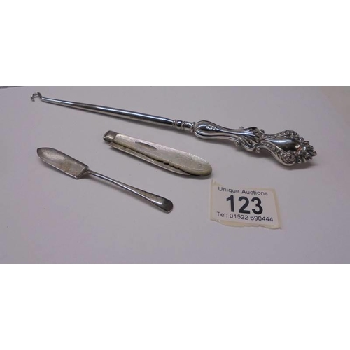 123 - A silver pen knife, a silver jam spoon and a silver handled button hook.