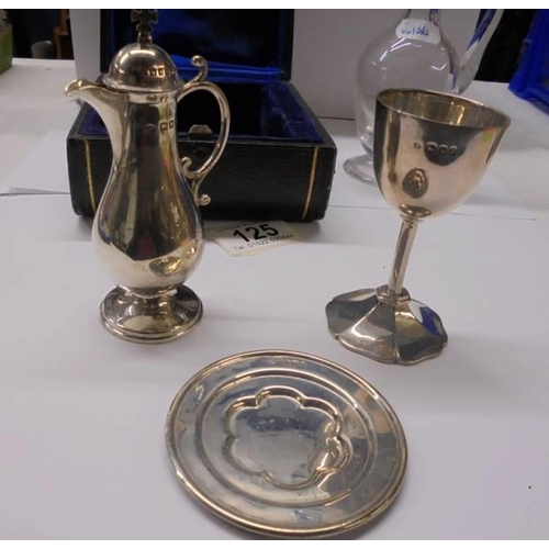 125 - A three piece cased silver Holy communion set and a glass ewer with silver topped cork.