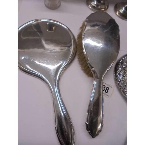 138 - Two silver hand mirrors, a silver hair brush, silver lidded pot and pair of silver candlesticks.