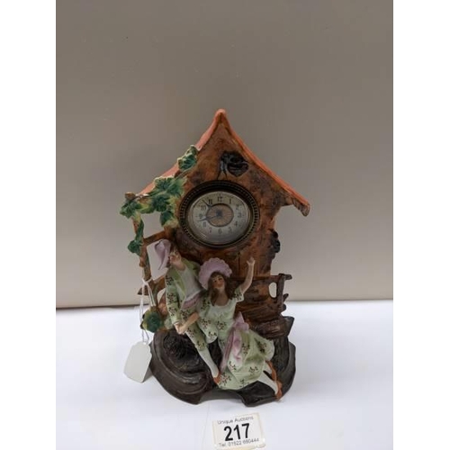 217 - A bisque porcelain mantel clock featuring a boy and girl.