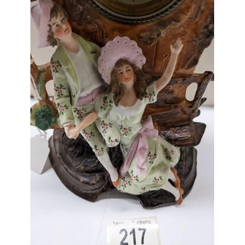 217 - A bisque porcelain mantel clock featuring a boy and girl.