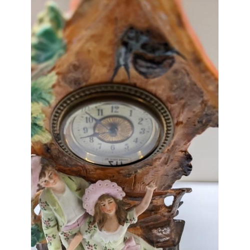 217 - A bisque porcelain mantel clock featuring a boy and girl.