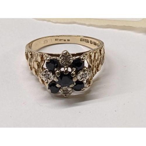 99 - A diamond sapphire cluster ring, hall marked for London 1975, textured shoulders, in 9ct gold, size ... 