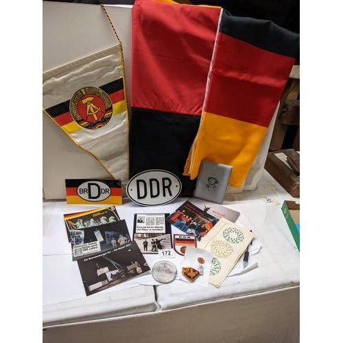 172 - A box of East German ephemera including flags, car badges, pin badges, medalliion and postcards.