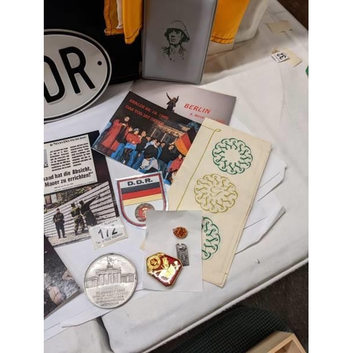 172 - A box of East German ephemera including flags, car badges, pin badges, medalliion and postcards.