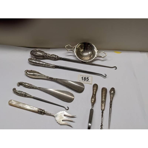 185 - A mixed lot of shoe horns, button hooks etc., some with silver handles, and a plated tea strainer.