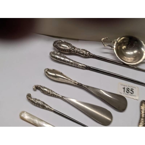 185 - A mixed lot of shoe horns, button hooks etc., some with silver handles, and a plated tea strainer.