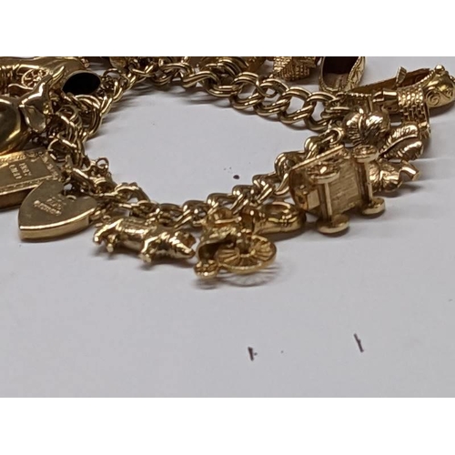 100D - A 9ct gold charm bracelet with 15 charms, in good condition, 41 grams.