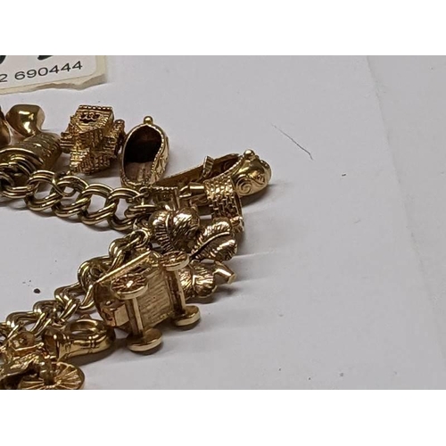 100D - A 9ct gold charm bracelet with 15 charms, in good condition, 41 grams.