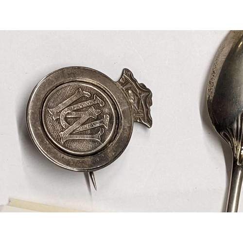 100L - Six silver spoons, a silver badge and one other silver item 54.5 grams.