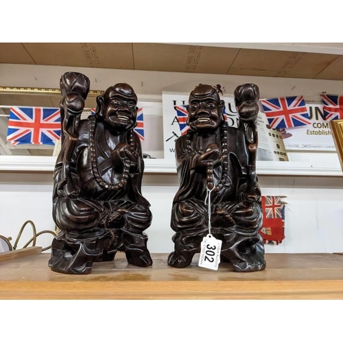 302 - A pair of late 19th century Chinese figural candle holders carved as Buddha's with bone teeth and ey... 