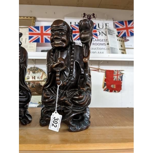 302 - A pair of late 19th century Chinese figural candle holders carved as Buddha's with bone teeth and ey... 