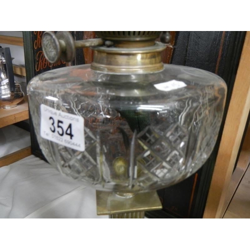 354 - A Victorian oil lamp with brass column, glass font and later shade.