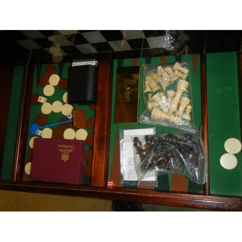 401 - A chess table with glass top and storage compartment with contents.