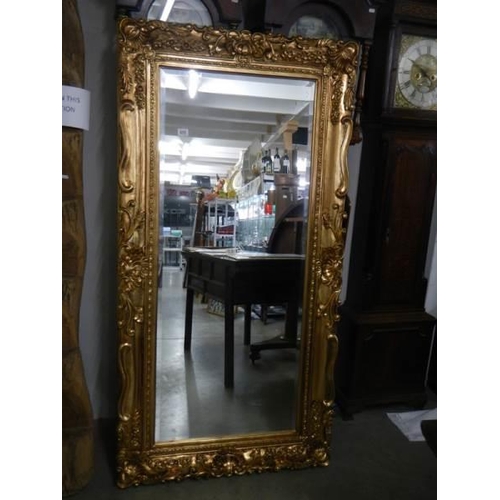 650 - A large rectangular bevel edged mirror in gilded swept frame. 88 x 175 cm.