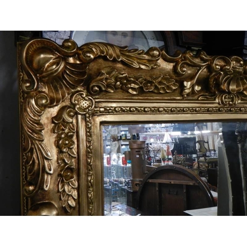 650 - A large rectangular bevel edged mirror in gilded swept frame. 88 x 175 cm.