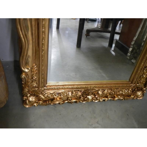 650 - A large rectangular bevel edged mirror in gilded swept frame. 88 x 175 cm.