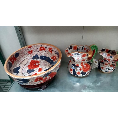 520D - A collection of ironstone Imari dragon handled graduated jugs together with a large Imari bowl on a ... 