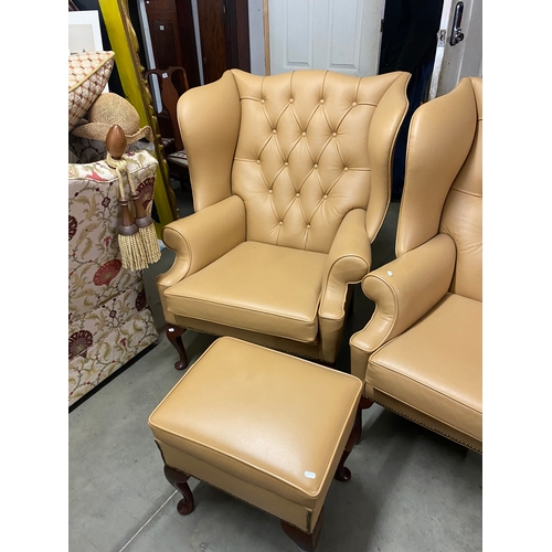 500B - Two large tan leather wingback chairs and a matching foot stool