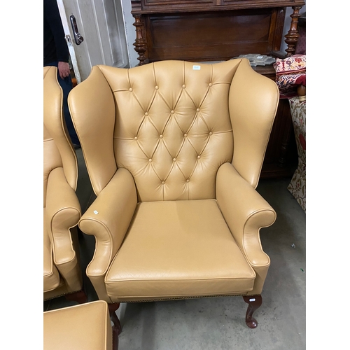 500B - Two large tan leather wingback chairs and a matching foot stool