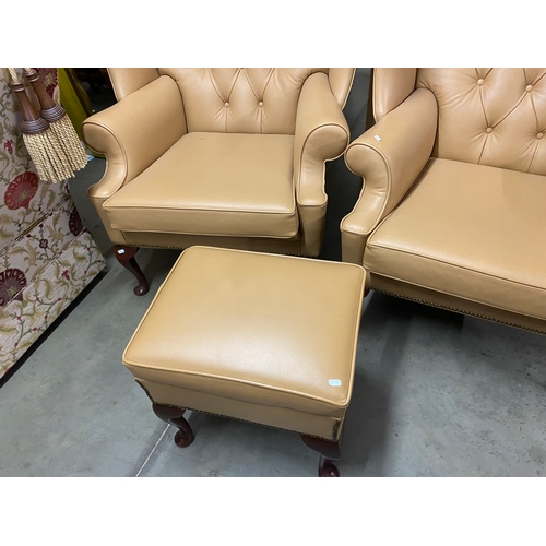 500B - Two large tan leather wingback chairs and a matching foot stool