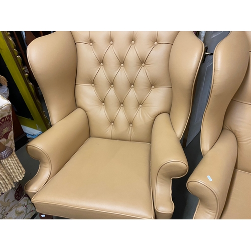 500B - Two large tan leather wingback chairs and a matching foot stool