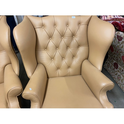 500B - Two large tan leather wingback chairs and a matching foot stool