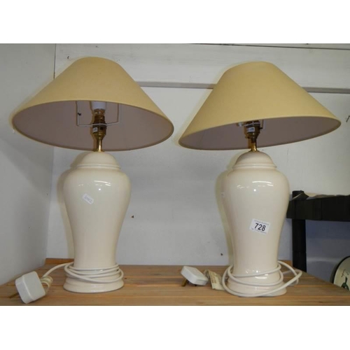 728 - A pair of cream pottery table lamps with shades, height 62 cm.