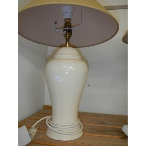 728 - A pair of cream pottery table lamps with shades, height 62 cm.