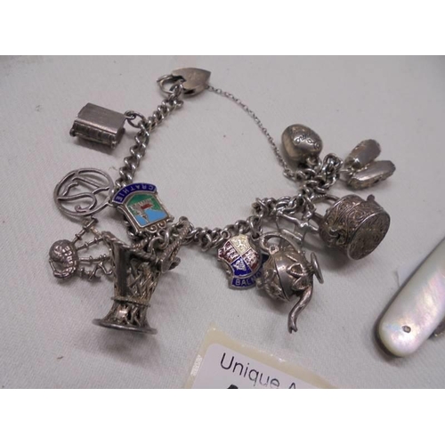 1037 - A silver bracelet with charms (42 grams) and a silver fruit knife.