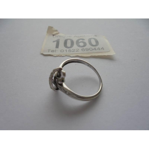 1060 - A diamond twist ring in 9ct white gold with diamond set shoulders, size K half.