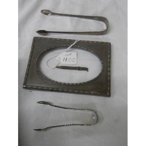 1100 - A silver photo frame, two silver sugar tongs and a silver pencil.