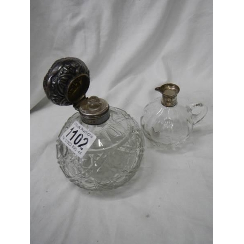 1102 - A silver topped perfume bottle and a glass jug with silver spout missing stopper.