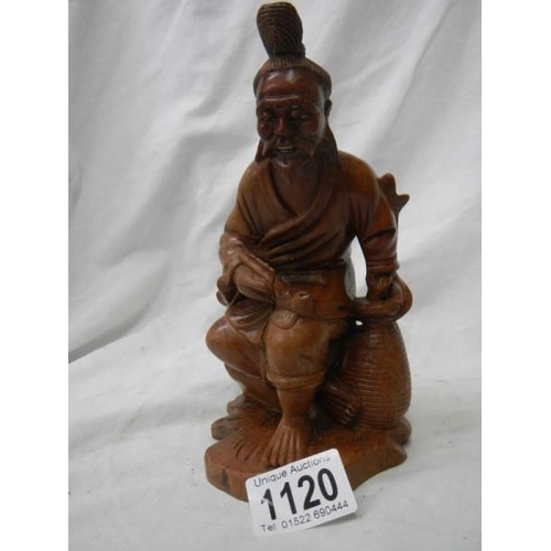 1120 - A carved wood figure of an oriental gentleman with bone teeth,