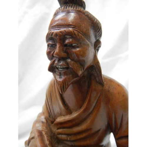 1120 - A carved wood figure of an oriental gentleman with bone teeth,